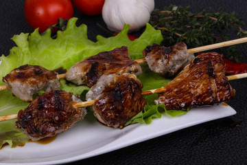Pork kebab skewers in the plate with salad leaves and tomatoes