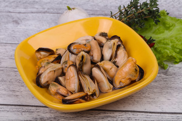 Pickled mussels in the bowl served pepper, garlic and salad
