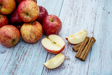 Organic ripe apples and cinnamon sticks on a wooden table. Fresh cut apple. Cooking ingredients. Harvest.