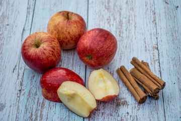Organic ripe apples and cinnamon sticks on a wooden table. Fresh cut apple. Cooking ingredients. Harvest.