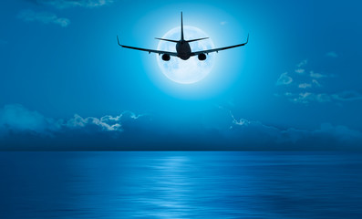 Passenger airplane in the sky against blue full moon "Elements of this image furnished by NASA "