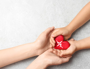 Woman and child holding heart on grey stone background, top view with space for text. Donation...