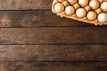 Chicken eggs in box on wooden table with copyspace. Top view