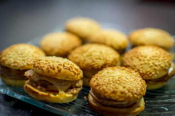 small or mini hamburgers or cheeseburgers, crunchy, on a glass plate, close-up, background defocused