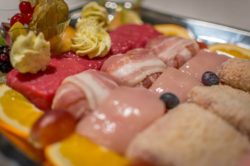 Gourmet meat pieces, including chicken, beef and bacon on a plate in close-up
