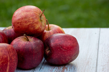 Organic ripe apples on a wooden table in the garden. Cooking ingredients. Harvest.