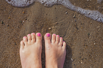 Top view of two female feet isolated on sunny wet sand of seashore. Happy woman enjoy summer...
