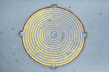 Round metal sewer cover on the background of urban asphalt pavement.