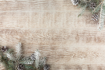 Christmas tree branch with pine cones on rustic wooden table. Winter background with copy space. Top view. Flat lay