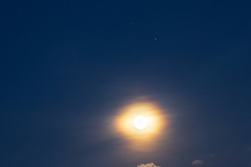 Full moon shining glowing light through a twilight sky with star. Long exposure for beautiful nature background.