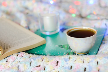 Light plaid, on it a tray with a Cup of tea and a candle, an open book and a garland