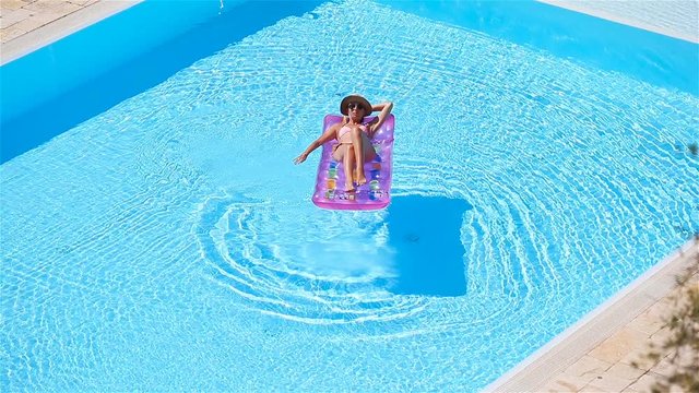 Young woman in bikini air mattress in the big swimming pool