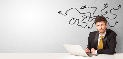 Businessman sitting at desk with direction concept