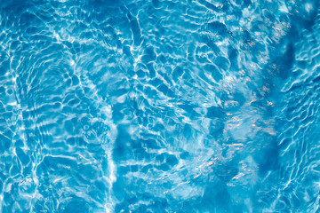 Background of rippled pattern of clean water in a blue swimming pool