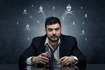 Loser drunk man sitting at table with skulls concept around