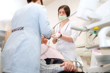 Doctor dentist and assistant doing dental operation of senior man patient in dental office. Dental fillings. Dental care for elder people.