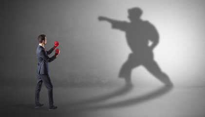 Fototapeta na wymiar Businessman fighting with his strong karate man shadow