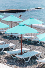 Fototapeta na wymiar Sun beds with umbrellas on a pebble beach
