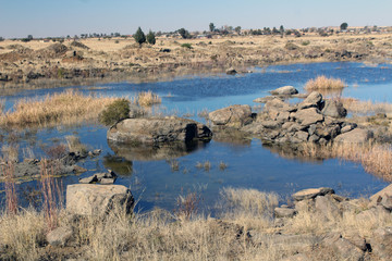 Landscape of Free State in South Africa with dam with blue water under blue sky