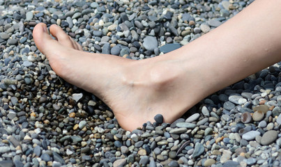 Feet girls on the beach with pebbles
