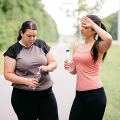 Group workout, sport and healthy lifestyle, motivation. Fit and overweight women friends drink water and rest after outdoor jogging