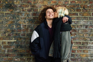 Fototapeta na wymiar Young couple enjoying Camden town in front of a brick wall typical of London