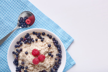 Obraz na płótnie Canvas Image of healthy breakfast, plate with oatmeal and berries and spoon, raspberries and blueberries with porridge. Healthy eating and diet concept. Healthy breakfast for family. Copy space fpr promotion