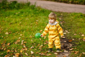 Concept: family, kids. Happy little child, baby boy laughing and playing with green ball in the autumn on the nature walk outdoors at park