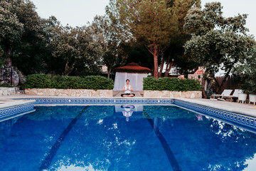 Portrait of young woman (fitness, yoga, healthy body) at the swimming pool. Freedom Concept. Outdoors. Yoga and mindfulness healthy lifestyle