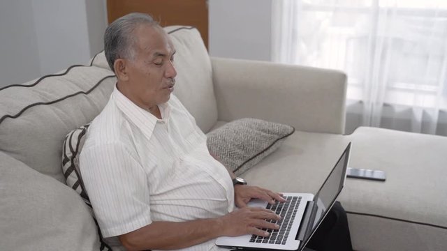 busy senior asian man working from home. old man using laptop at livingroom