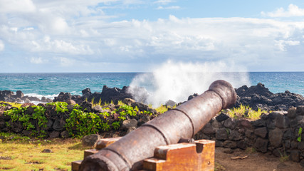 Vieux canon devant une mer agitée frappant un littoral rocheux