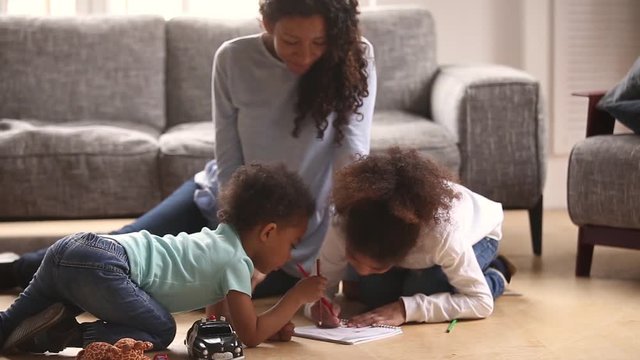 African mother and little kids sitting on warm floors drawing