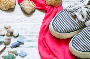 blue striped sneakers with pink  towel, shells and stones.