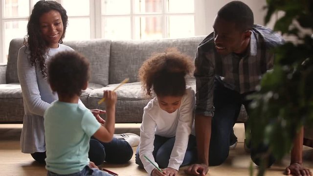 Kids drawing spending free time with parents on warm floor