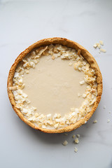 Coconut custard pie with coconut crisps on marble background