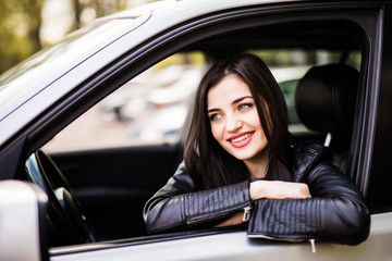 Fototapeta na wymiar Beautiful girl in jacket is smiling while driving a car