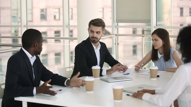 Diverse businesspeople in formal wear negotiating during meeting in boardroom