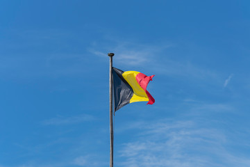 The Belgian flag, tricolor, with a nice blue sky as background