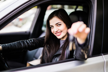 Beautiful young girl with car key in hand in her new car