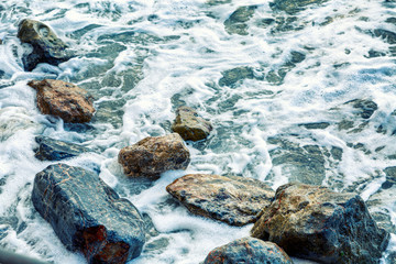 Foamy sea waves on large rocks on the shore. Close-up. Background. Space for text.