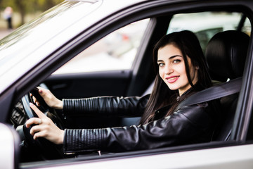 Obraz na płótnie Canvas Beautiful young happy smiling woman driving her new car