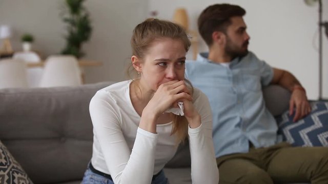 Couple in quarrel sitting on couch focus on crying girl