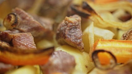 Tasty juicy baked pieces of meat with potatoes just from the oven - extreme close up.