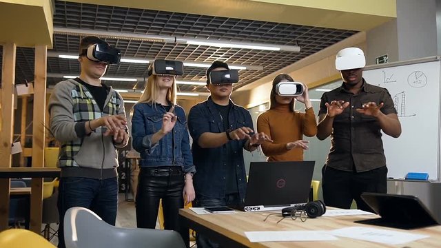 Group of hipster people typing something in vr virtual reality glasses during work day.