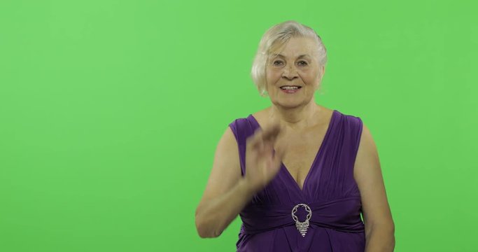 An elderly woman waving to camera and smiles. Old grandmother. Chroma key