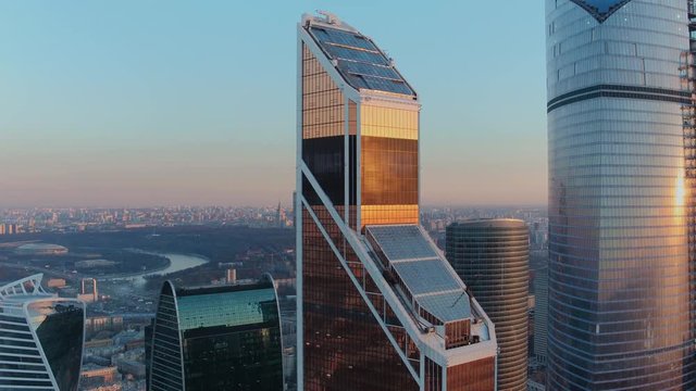 Flying over the Moscow city - a business district with futuristic glass skyscrapers and setting sun reflecting in them