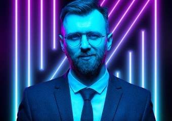 Young handsome model posing in a studio in a trendy neon light. Fashionable man in a stylish suit. Vibrant color. Bright colorful light effects. Disco style. Overlay. Gel filter. Supersaturated