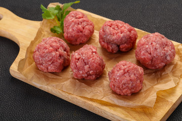 Raw meatball over wooden background
