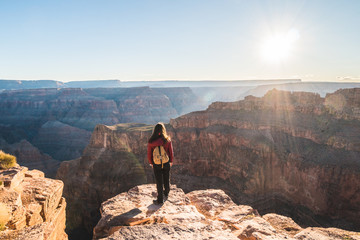 Girl solo traveler on the edge of a cliff watching a beautiful view of Grand Canyon West Rim