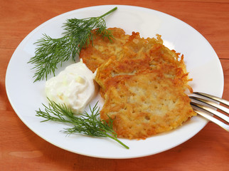 potato pancakes with sour cream on a rustic table
